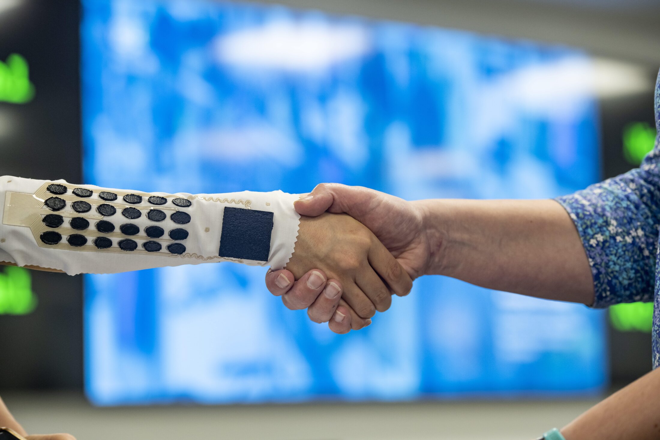 A person shakes hands with someone wearing a sensor on their arm