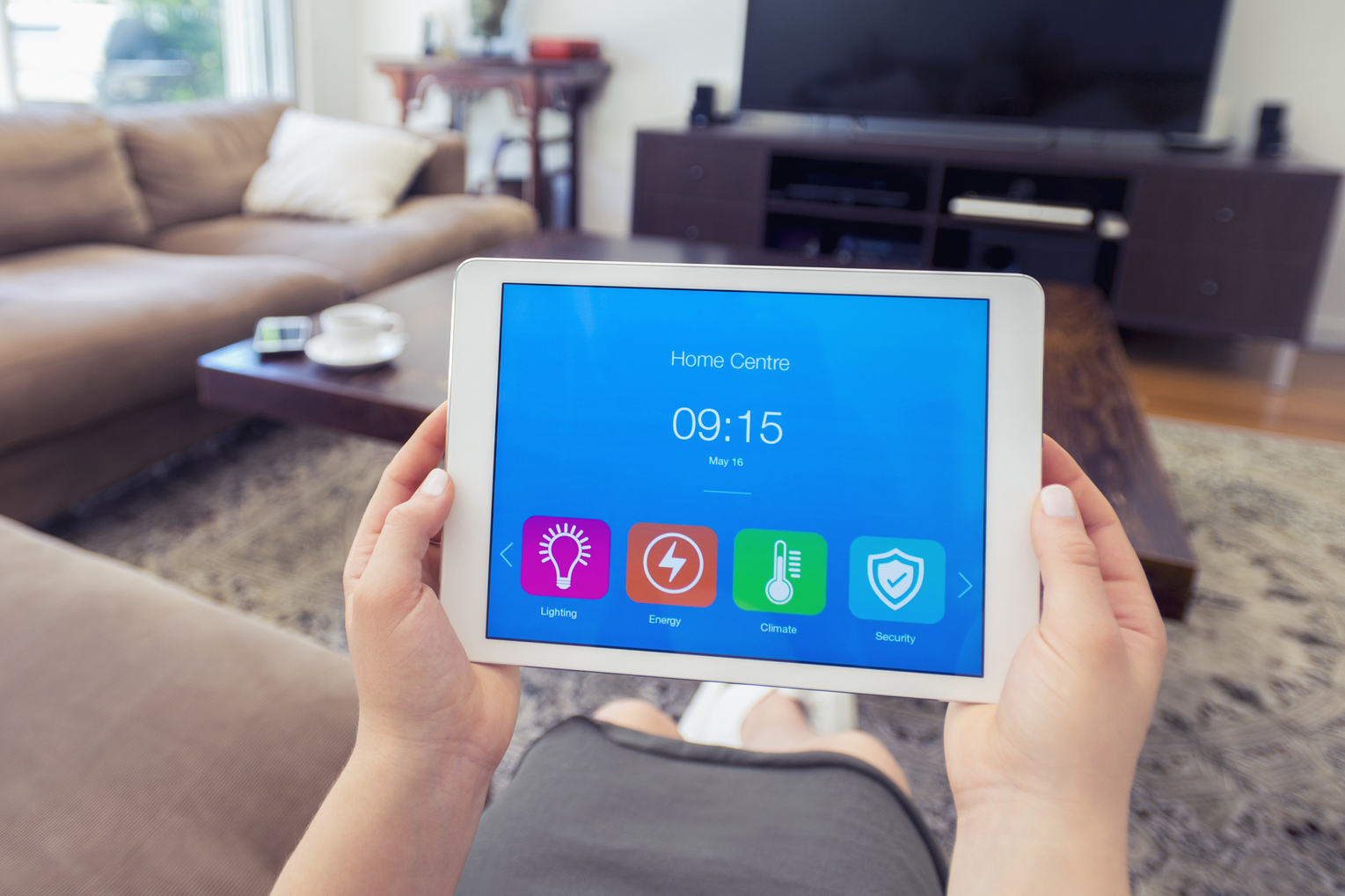 A person holding a tablet showing apps for controlling systems in the home