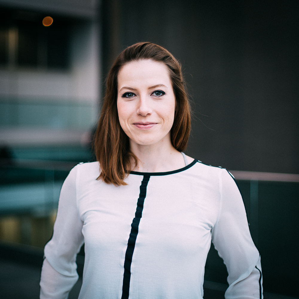 A smiling woman, Dr Christine Evers, with long light brown hair, wearing a white blouse featuring a vertical black line down the centre and around the neckline.