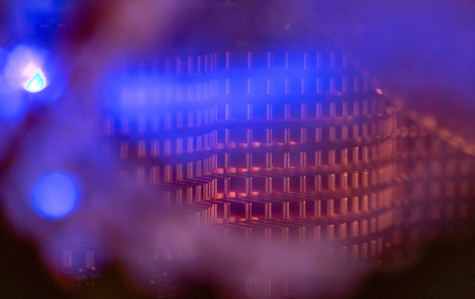 Abstract image with blue and copper grid-like pattern and a prominent blue light on the left.