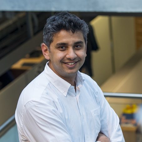 A smiling man, Professor Gopal Ramchurn, with dark grey hair, wearing a white shirt.