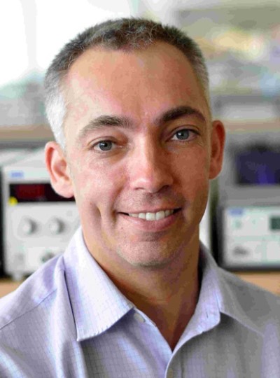 A smiling man, Professor Steve Beeby, with short grey hair, wearing a light purple shirt with small squares pattern.